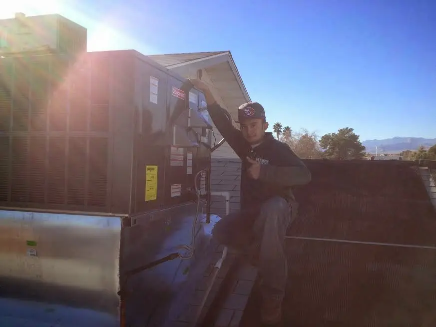 HVAC technician performing Heat Pump Repair on a rooftop unit in Elon